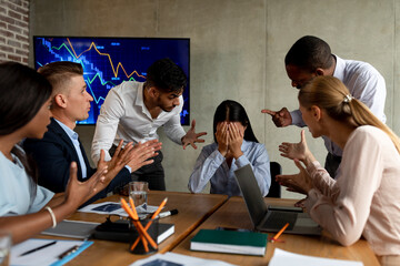 A group of coworkers aggressively confronts a stressed female employee in an office setting. They blame her for a business project's failure, causing visible distress.