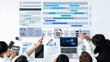 A diverse group of business professionals discussing project management strategy while reviewing Gantt chart and task list on a collaborative workspace. Gantry