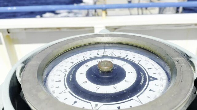 Close up of a marine gyrocompass on a ship deck, traditional nautical navigation instrument against the blue ocean background during a voyage.
