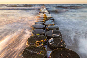 Buhnen in Wustrow an der Ostsee bei Sonnenuntergang mit Wellen in der Langzeitbelichtung