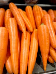 fresh whole carrots. a close up view of pile of fresh, orange carrots with smooth skin, arranged upright and filling the frame