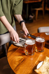 Two fresh beer mugs on wooden table