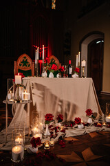Candlelight date in restaurant. Tablecloth and rose petals on floor. Surprise for marriage proposal. Detail decor. Valentine's Day evening, burning candles. Romantic dinner setup for couple at night.