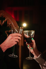 Cheers. Couple in love drinking wine. Romantic date by candlelight at night. Hands man and woman hold glasses at home. Toast. Dinner setup table for couple on Valentine's day. Proposal hand and heart.