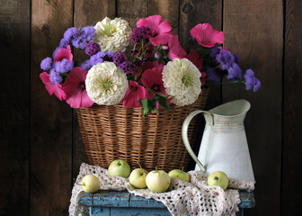 Rustic still life with colorful flowers lavatera, ageratum, zinnia, apples, and vintage pitcher