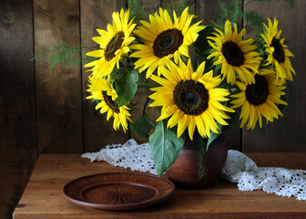 Sunflowers bouquet in rustic vase with clay plate