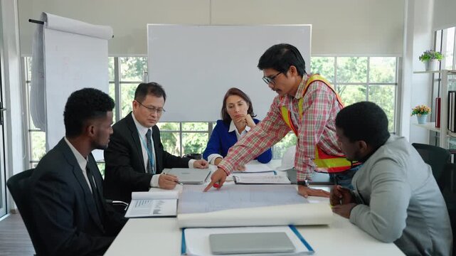 A diverse team of professionals gathers around a table, studying architectural blueprints and discussing project details. The scene showcases teamwork, planning accuracy, and coordination across engin