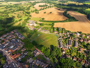Aerial view of a vibrant tapestry of golden fields, lush green golf courses, and quaint residential areas, Hook, England, United Kingdom.