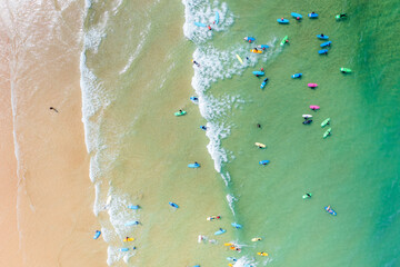 Aerial view of the vivid turquoise waters meet the golden sands, dotted with surfers enjoying the waves off the coast., Newquay, England, United Kingdom.