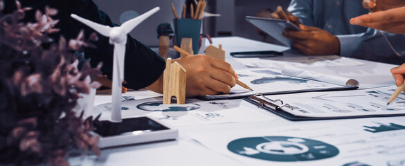 A vibrant workplace scene showcasing a collaborative meeting focused on sustainable strategies, with hands actively engaging with charts and eco-friendly models on the table. SACTR