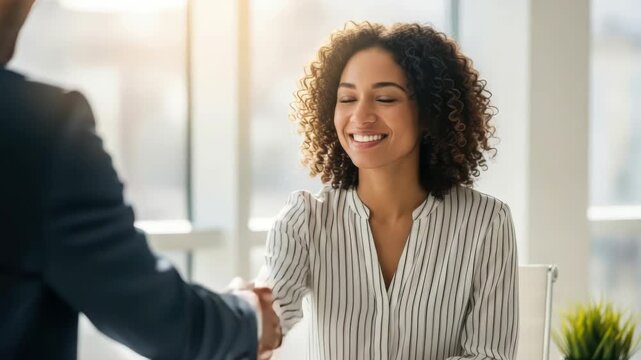 Businesswoman Smiling During Professional Handshake in Bright Modern Office