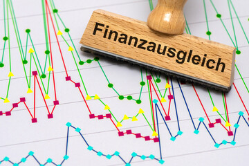 Ein Holzstempel ist beschriftet mit dem Aufdruck Finanzausgleich