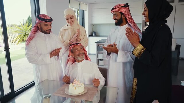Arab family members celebrating a father's or grandfather's 60th birthday, gathering around him with warm smiles and a simple cake, showing strong love and family bonding - Powered by Adobe