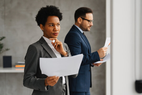African American businesswoman and businessman reviewing documents in an office. - Powered by Adobe