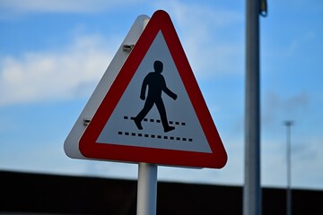 Pedestrian Crossing Warning Sign Against Blue Sky and Clouds