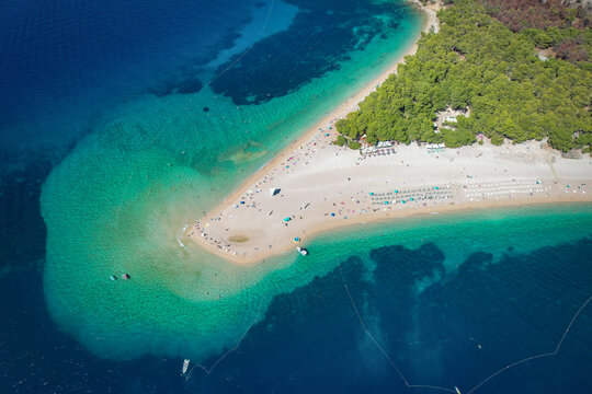Aerial view of the iconic Zlatni Rat beach, where turquoise waters meet the golden sand, creating a stunning contrast against the lush green forest, Bol, Split-Dalmatia County, Croatia.