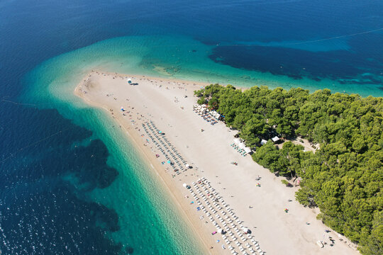 Aerial view of Zlatni Rat beach, a golden sandspit stretching into the turquoise Adriatic Sea, fringed by verdant pine forests, Bol, Croatia.