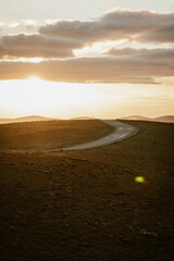 Vertical image of an empty mountain road between the hills of the outback outdoor during a golden sunset with sun flare in Flinders Ranges in Australia with space for text.