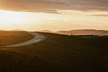 Beautiful landscape with an empty mountain road between the hills of the outback outdoor during a golden sunset with sun flare in Flinders Ranges in Australia with space for text.
