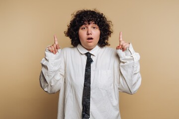 Person with curly hair in oversized shirt and tie pointing upwards