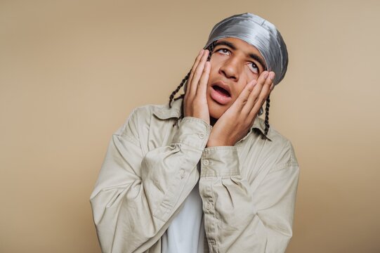 Young man with braided hair and durag expressing surprise.