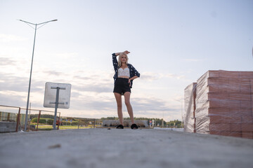 Young woman with blonde hair stands confidently on construction site, wearing casual outfit, surrounded by building materials, showcasing strength and determination in a dynamic outdoor environment