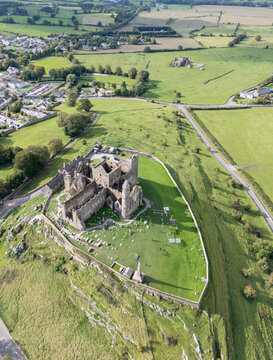 Aerial view of the Rock of Cashel, a medieval complex with its imposing cathedral ruins standing proudly against the backdrop of vibrant green fields, Cashel, County Tipperary, Ireland.