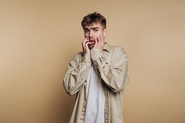 Fototapeta premium Young man with surprised expression against beige background