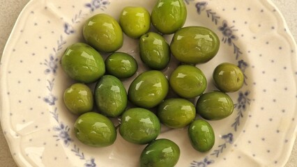 Green olives serving on patterned ceramic plate
