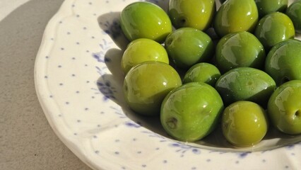 Fresh green olives serving on decorated ceramic plate