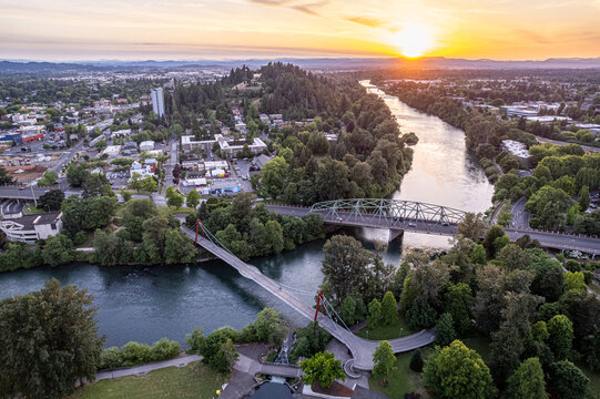 Aerial view of sun kissing Skinner Butte as the Willamette River winds through the city under bridges, painting a serene urban landscape, Eugene, Oregon, United States.