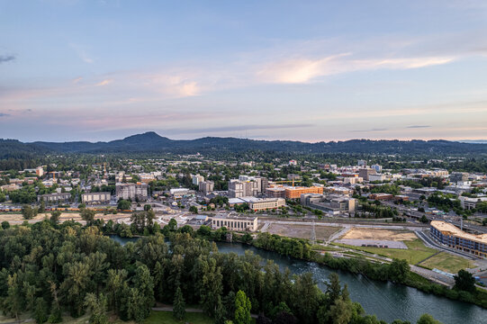 Aerial view of the Willamette River winding through Eugene, with Skinner Butte rising in the distance under a soft, pastel sky, Eugene, Oregon, United States.