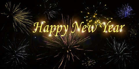 Jahreswechsel mit verschieden Silvesterraketen und der Schrift Happy New Year mit Glitzerpunkten am schwarzen Himmel

