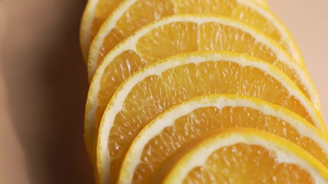 A fan of thin orange slices rotates, showing repeated citrus patterns and rind edges. The close-up composition feels fresh, bright, and minimal.