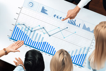 A diverse group of professionals engaging in a collaborative business meeting, analyzing interactive data trends on graphs to drive strategic decision-making processes. Scalp