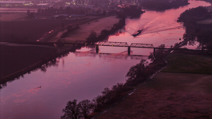 Sonnenuntergang &uuml;ber dem Fluss mit einem Schiff und einer Br&uuml;cke im Hintergrund