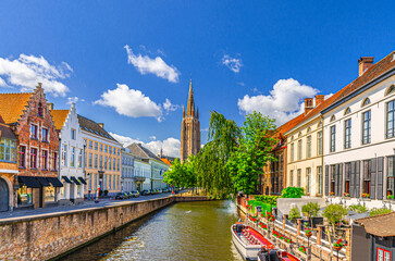Obraz premium Bruges cityscape, Church of Our Lady Gothic style with tower, Dijver water canal embankment, tourists boat near wharf, medieval buildings in Brugge old town quarter, West Flanders province, Belgium
