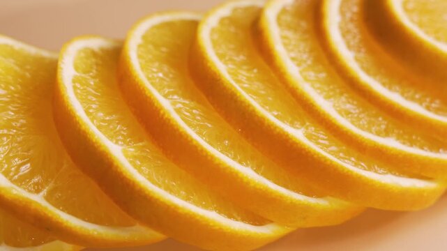 Curved orange wedges rotate in a stacked row, creating a rhythmic citrus pattern. Soft focus and warm light highlight juicy flesh and rind.