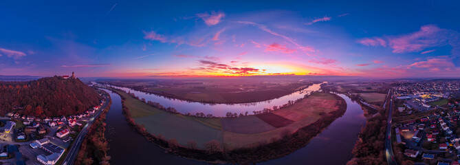 Sonnenuntergang &uuml;ber einem Fluss mit H&uuml;gel und Stadt