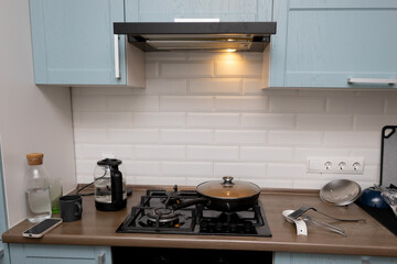 A frying pan with food is on the kitchen stove. Food is being cooked in the kitchen at home.