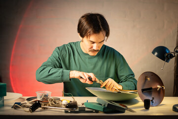 Upcycling master works at table on refurbishing vintage lamp, renewing wiring system and fixing...