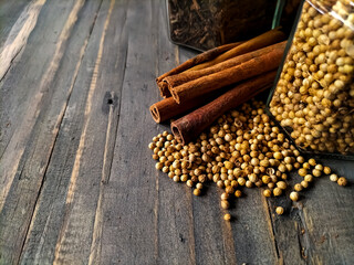 Cinnamon sticks, cloves, and coriander seeds are arranged on a rustic wooden surface.