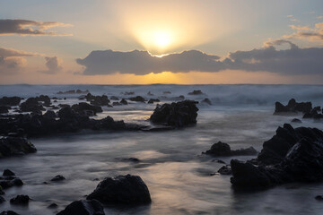 Obraz premium Panoramic image of a sunset in the Azores showing the sun setting over the sea, with large rocks emerging from the water