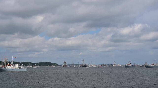 Segelboote und Yachten auf ruhigem Wasser mit bewaldeter K&uuml;stenlinie und bew&ouml;lktem Himmel, Windjammer Parade Kiel 2025, Heikendorf, Kreis Pl&ouml;n, Kieler F&ouml;rde, Schleswig-Holstein, Deutschland, Europa 