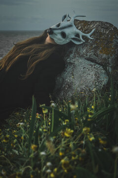 mujer con mascara de ciervo posada en una pidra