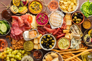 Enjoy a vibrant charcuterie board filled with assorted cheeses, savory sausages, creamy hummus, nuts, and colorful vegetables. Perfect for sharing at a casual gathering