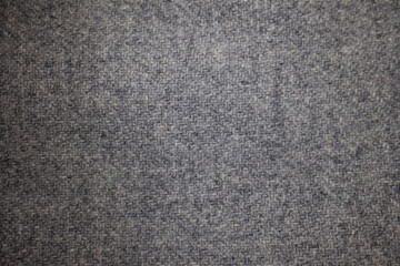 Detailed macro shot of a gray melange woolen textile. The soft, warm texture with a classic woven pattern makes a perfect natural background or surface.