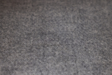 Detailed macro shot of a gray melange woolen textile. The soft, warm texture with a classic woven pattern makes a perfect natural background or surface.