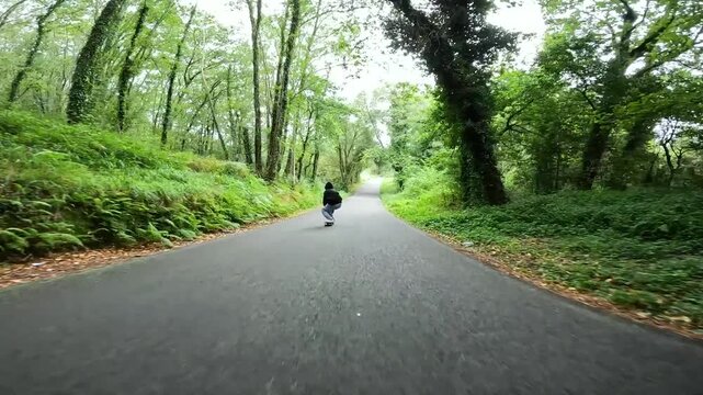 hombre joven patinando en una carretera en el bosque