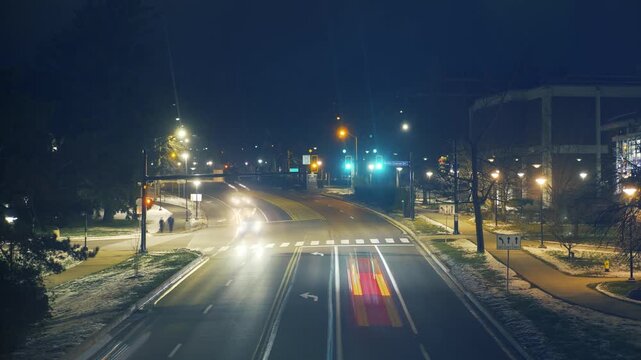 A nighttime timelapse of traffic along North Atherton Street in State College, Pennsylvania, with glowing headlights, red lights, and winter scenery framing the busy roadway. Day version available. 14